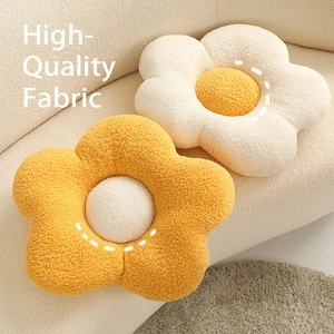 Minimalist flower-shaped plush throw pillows in white and yellow on a sofa