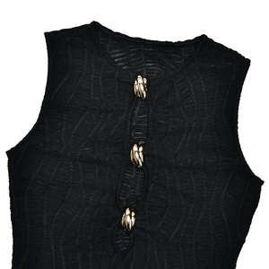 Détail d'une robe noire sans manches avec tissu froncé et trois boutons dorés décoratifs