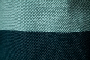 Makroaufnahme von minzgrünem und dunkelblauem Strickstoff mit Netzstruktur-Details