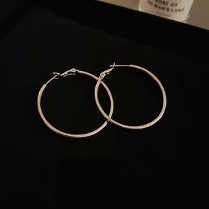 Macro shot of minimalist silver geometric C-shape hoop earrings on black background