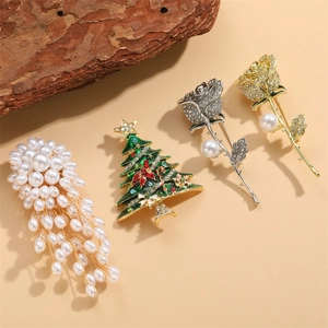 Set aus Weihnachtsbaum- und Rosenbroschen mit Kristallen und Perlen auf beigem Grund