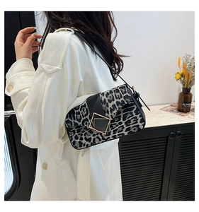 Close-up of leopard print bag with black flap, gold square buckle, and thin strap