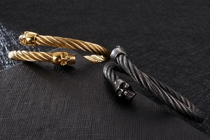 Détail de bracelets câbles torsadés avec têtes de mort en finitions or et argent vieilli