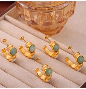 Detail view of five gold-tone C-shaped earrings with green and white stone inlays