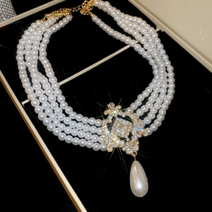 Détail d'un collier de perles à quatre rangs avec pendentif doré dans un coffret luxe