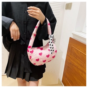 Detail of pink plush handbag featuring red heart patterns and a polka dot silk scarf handle