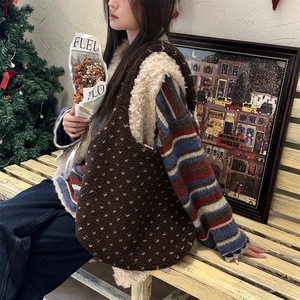 Side view of large brown faux shearling tote bag with white heart pattern in cozy setting