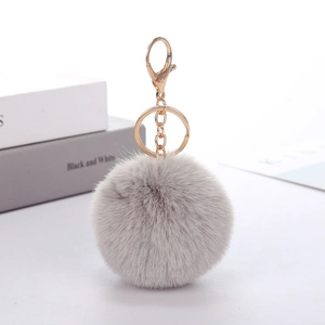 Detail of light grey faux rabbit fur pompom keychain with golden metal hardware