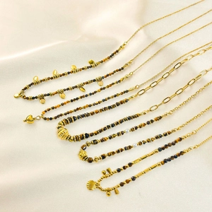 Detail view of tiger eye stone bead necklaces with gold charms on silk background