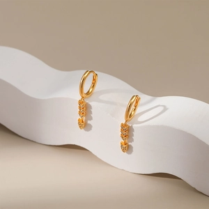 Detail of gold-plated arrow earrings with pavé zircons on wave-shaped art display
