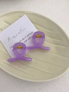 Detail of lavender translucent resin hair claws with gold metal spring on a ceramic tray