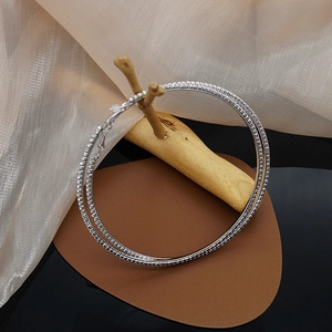 Close-up of oversized silver hoop earrings with three rows of sparkling rhinestones