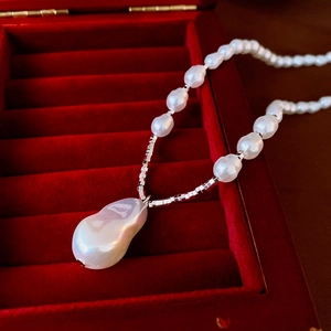 Clip d'oreille lune en zircon et collier perle baroque dans un écrin de velours rouge