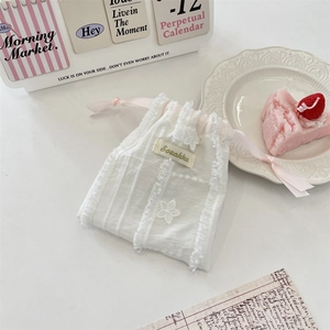 Lace drawstring pouch with floral embroidery and pink ribbons on a desk