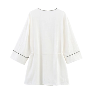 Detail of white cotton linen cardigan featuring black contrast piping and wide sleeves