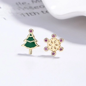 Detail of asymmetric Christmas tree and snowflake earrings with green enamel and purple zircons