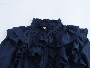 Detailed view of dark blue blouse with ruffled collar and size S tag on textured fabric