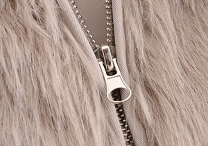 Close-up of high-quality metal zipper detail on a soft faux fur light brown coat