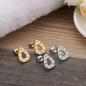 Elegant gold and silver teardrop earrings set with sparkling crystals on wood background