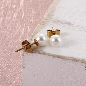 Elegant white round pearl earrings with gold-toned metal base on a soft pink background