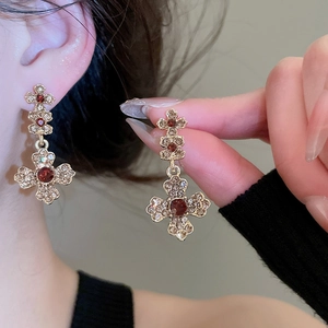 Detailed close-up of retro floral earrings with red gemstones and sparkling crystals