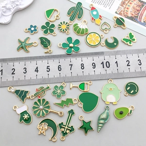 Gros plan de breloques en émail vert avec règle montrant la taille pour bijoux DIY
