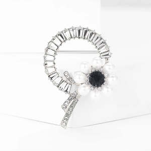 Macro detail of silver flower brooch with white pearls and sparkling zircons