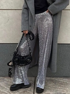 Women's sparkling silver sequin wide-leg pants paired with a grey coat for party wear