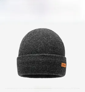 Detail showing dark grey knitted beanie texture and orange leather label with NY&JA text