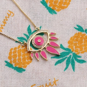 Detailed close-up of pink enamel Evil Eye pendant with zircon stones on gold box chain