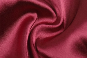 Primo piano dettagliato che mostra l'elegante drappeggio e la trama satinata del tessuto rosso