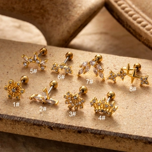 Detailed macro view of eight golden zircon cartilage earrings with assorted shapes