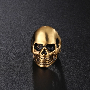 Punk style skull ring in antique gold finish with brushed texture on black background
