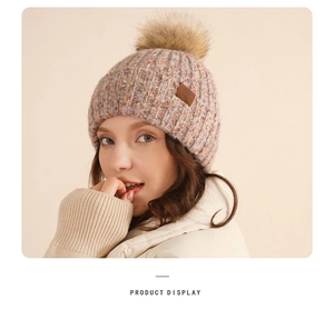 Detail showing knit wool texture with faux fur pompom and snowflake leather patch