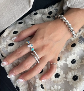 Detail of 925 sterling silver twist bracelet and rings with rainbow gemstone on hand