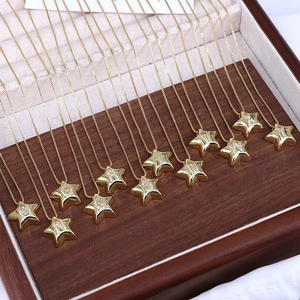 Close-up of gold star pendant necklaces with pavé zircon and initial letters in a box