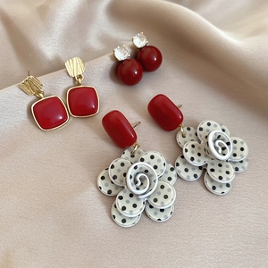 Detail shot of three vintage red enamel and pearl earrings on premium champagne silk fabric