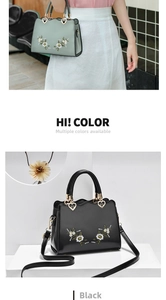 Detail of embroidered floral handbag with heart-shaped metal buckles and adjustable strap