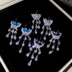 Detail of butterfly tassel earrings with pear-cut zircons on black velvet tray