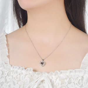 Silver heart projection necklace with central dark stone on model's neckline