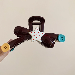 Detailed macro view of acrylic bow hair claw clip with star and button accents