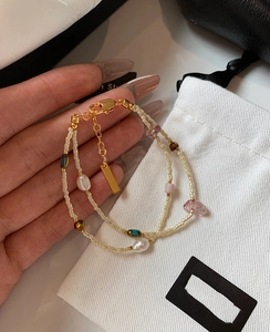 Detail of double-layer beaded bracelet featuring freshwater pearls and gold lobster clasp