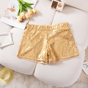 Detail von goldenen Pailletten-Shorts auf einem Sofa mit gemütlicher Dekoration