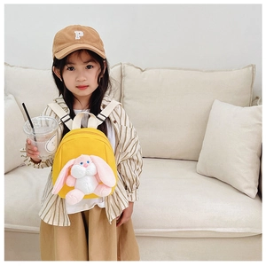 Close-up of yellow canvas toddler backpack with a cute white plush bunny pendant