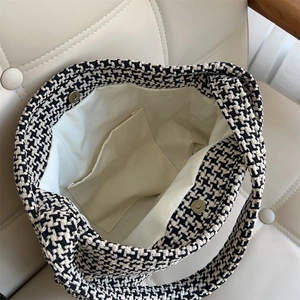 Detail view of houndstooth knit bag interior with cream lining and magnetic closure