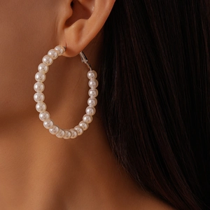 Close-up of elegant oversized white pearl beaded hoop earring worn by a model