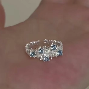 Irregular textured silver open ring with five blue zircon stones on person's hand