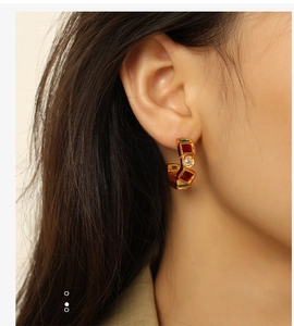 Close-up of 18K gold plated titanium ear studs featuring green and red natural stones