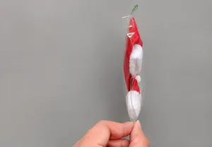 Macro shot of a mini red plush Christmas hat for wine bottles in transparent packaging