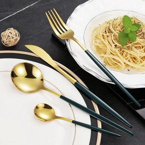 Gold and dark green stainless steel cutlery set on black marble, modern flatware kit